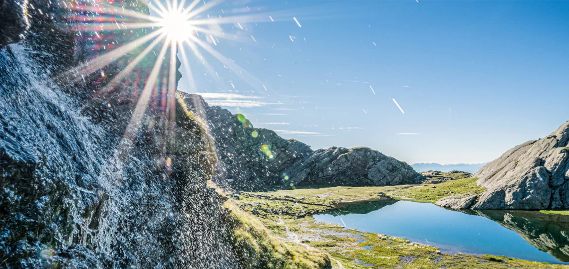 Panorama estivo di montagna con una fonte d'acqua in primo piano